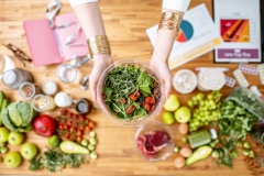 Dietitian holding salad above the table full of healthy food